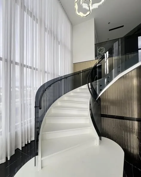 Curved glass on a spiral staircase with a black handrail
